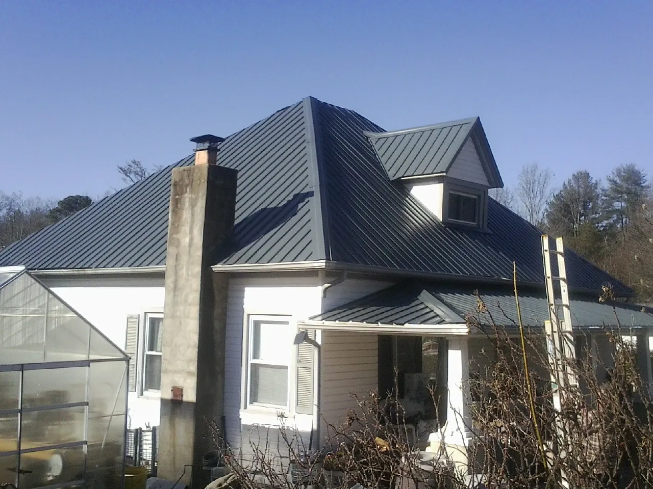 Dark blue standing seam metal roof on a white farmhouse with dormer — Slate & Tile Roof Repair by Roofing Brothers in Forney