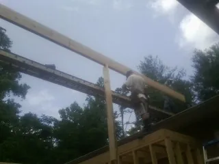 Carpenter setting a ridge beam over a new addition frame — Ice Dam Removal by Roofing Brothers in Forney
