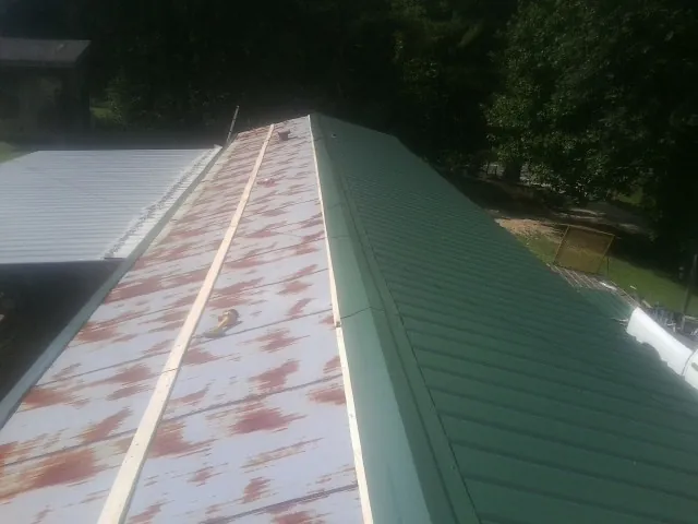 Old rusted panels beside newly installed green metal roofing — Wind Damage Roof Repair by Roofing Brothers in Forney