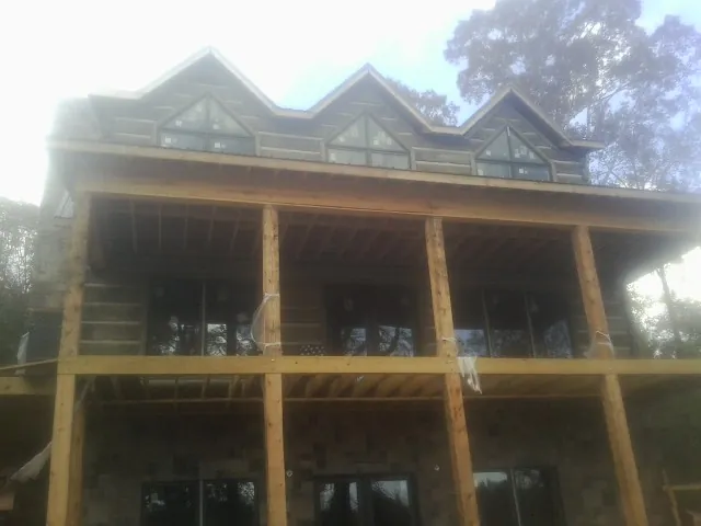 Dormers and porch framing on a large log home under construction — Roof Coating work by our crew in Forney