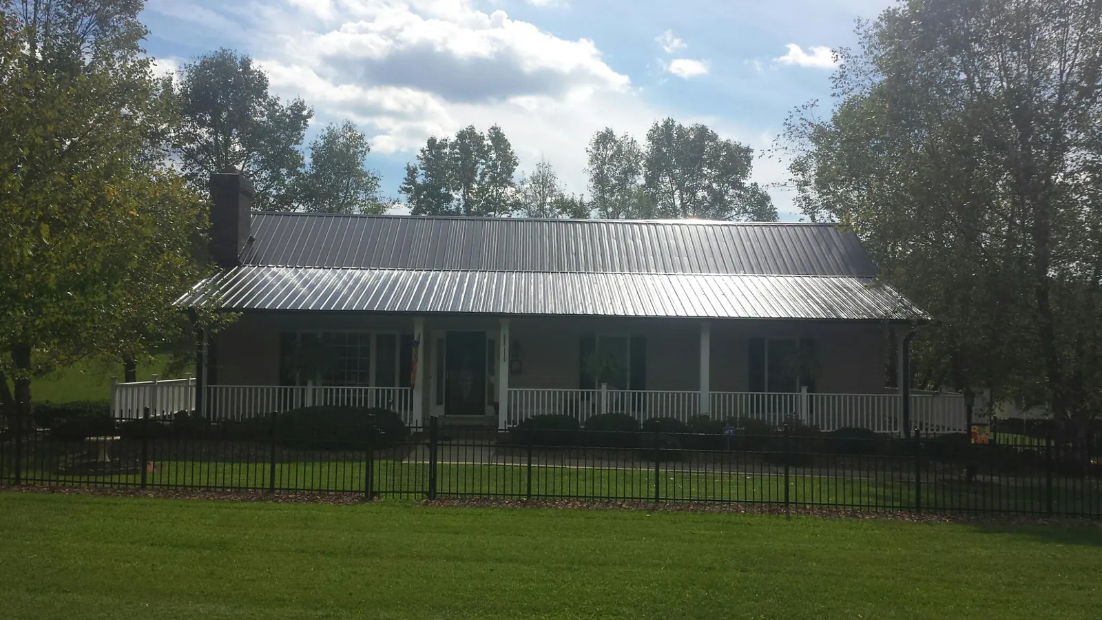 Gray metal roof on a brick ranch with a full width front porch — Gutter Guard Installation work by our crew in Forney